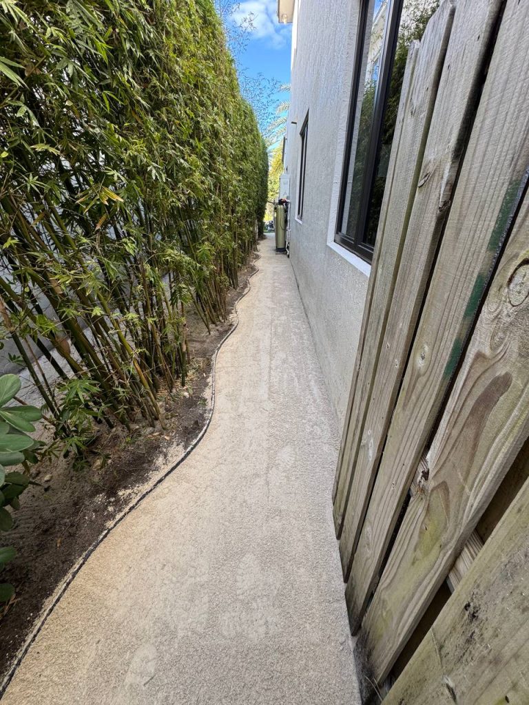 Exposed base during installation preparation in a narrow passage between a white wall and bamboo.