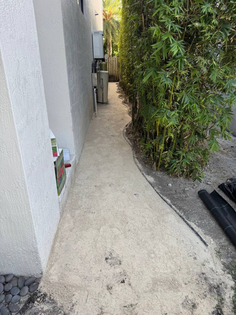 Exposed base during installation preparation in a narrow passage between a white wall and bamboo.