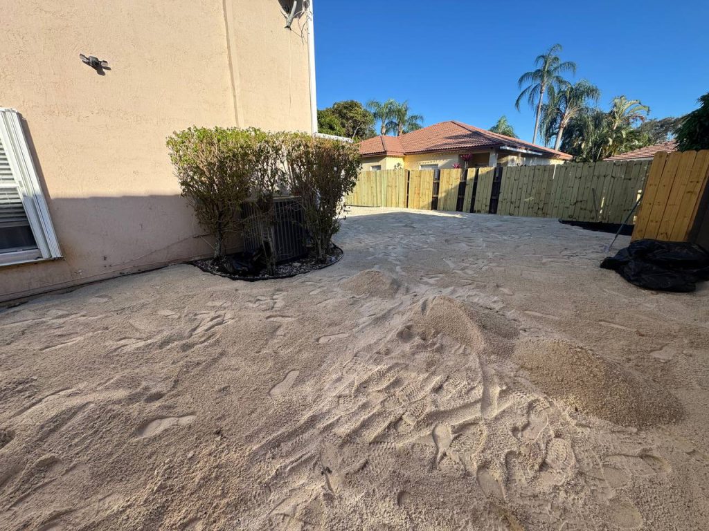 Exposed base during installation preparation beside a two-storey beige house and screened patio.