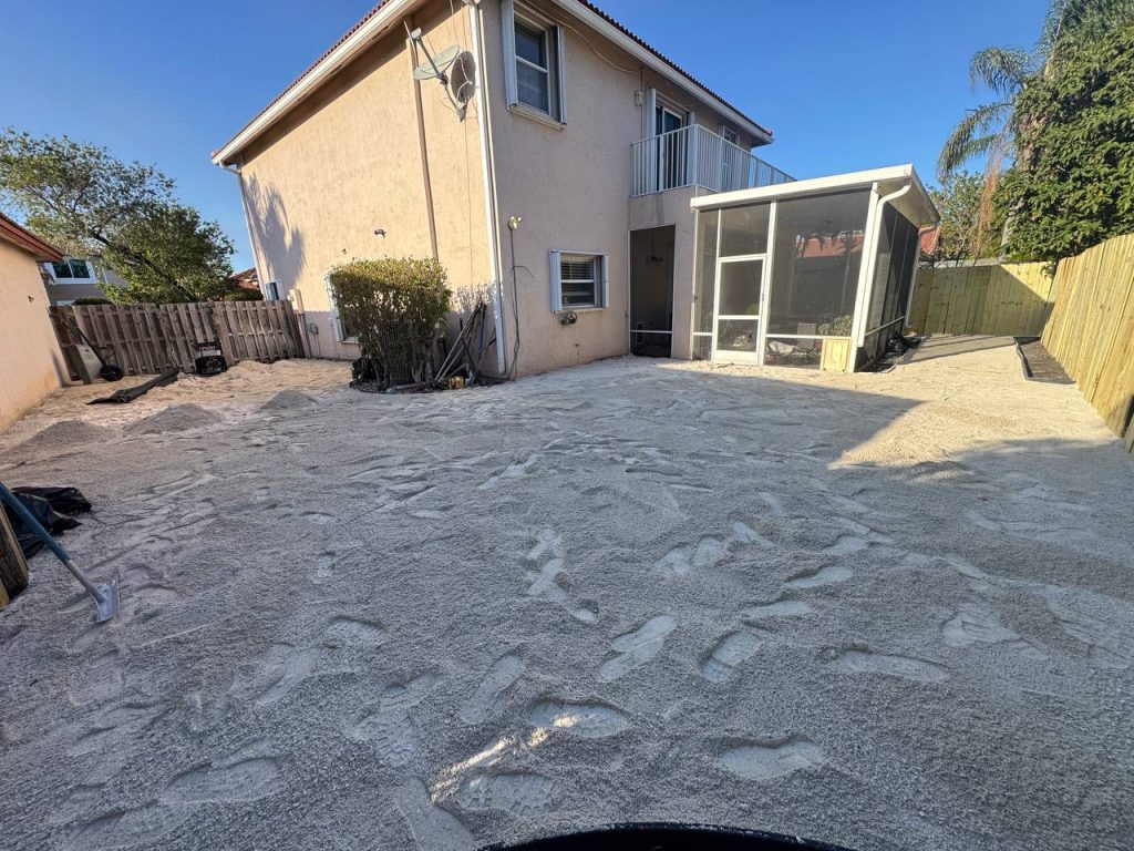 Exposed base during installation preparation beside a two-storey beige house and screened patio.