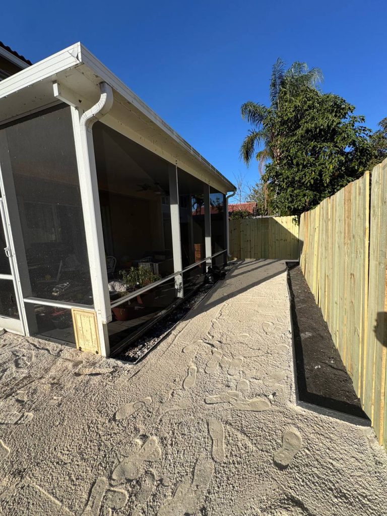 Exposed base during installation preparation beside a two-storey beige house and screened patio.