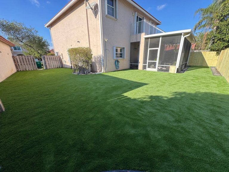 Artificial turf lawn beside a two-storey beige house and screened patio.