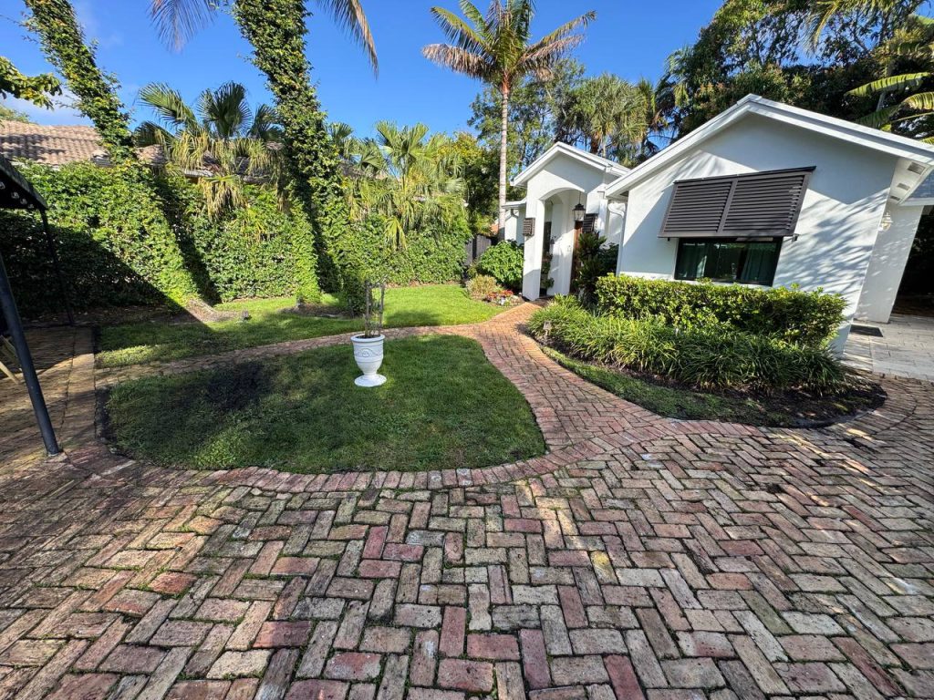 Earlier ground surface around palms and curved brick paths.