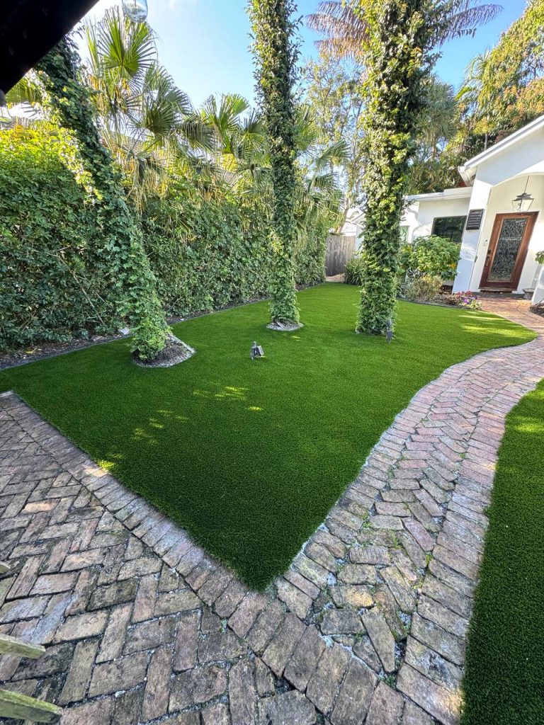 Turf lawn with palm trunks bordered by curved brick paths.