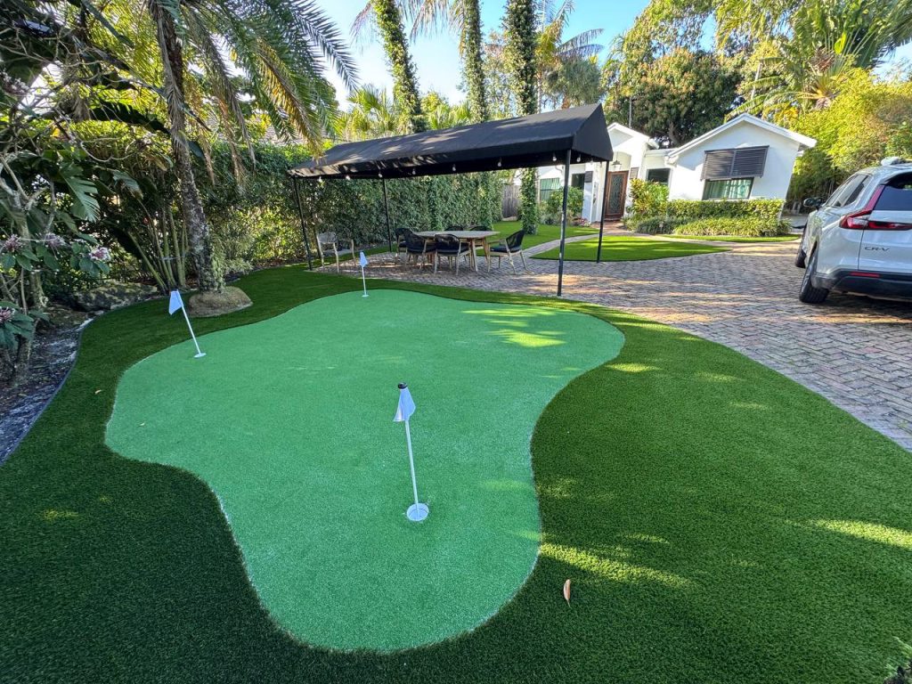 Putting green with flags beside palms and brick paths.
