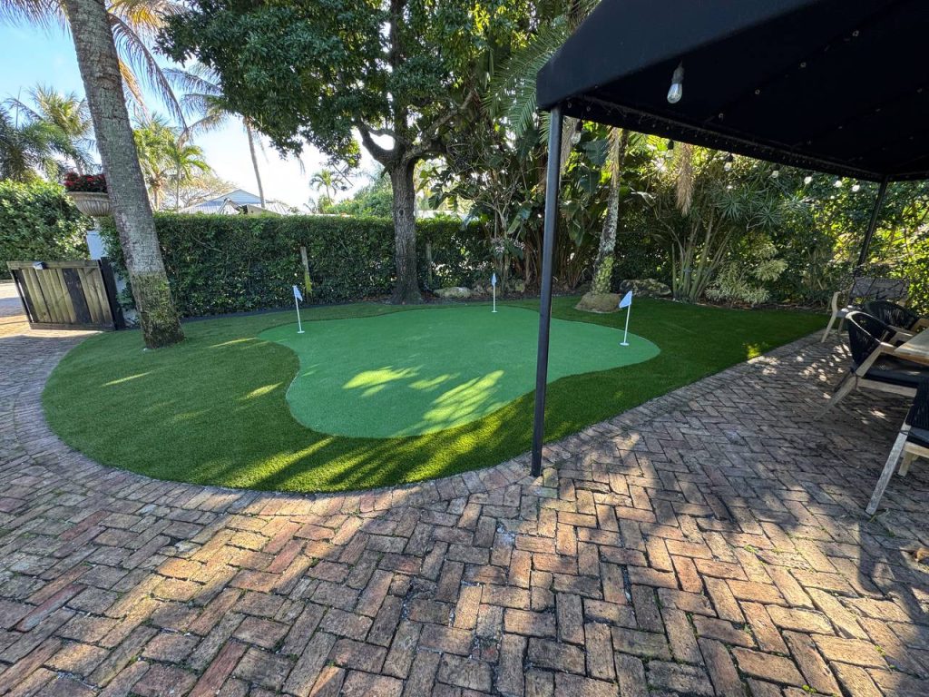 Putting green with flags beside palms and brick paths.