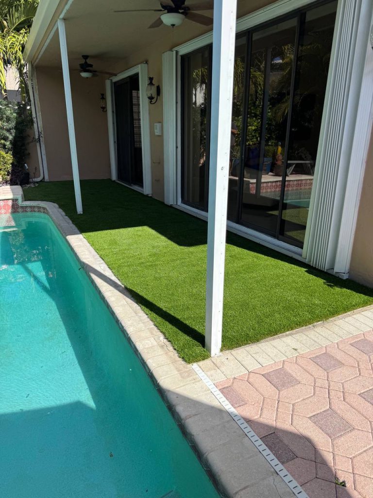 Turf beside sliding doors and a covered swimming pool patio.