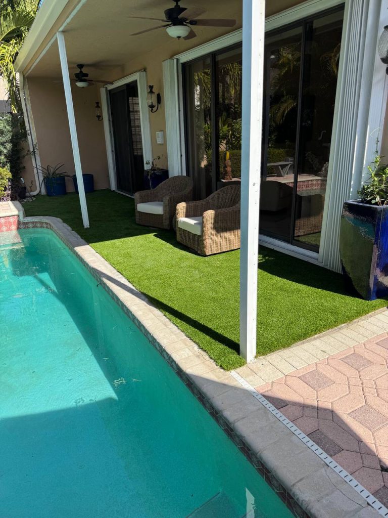 Turf beside sliding doors and a covered swimming pool patio.