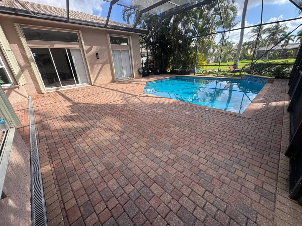 Earlier ground surface around a swimming pool inside a screen enclosure.