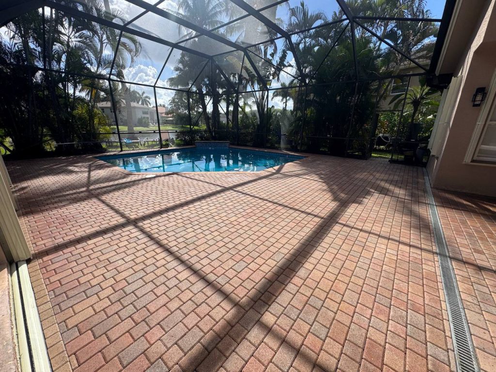 Earlier ground surface around a swimming pool inside a screen enclosure.
