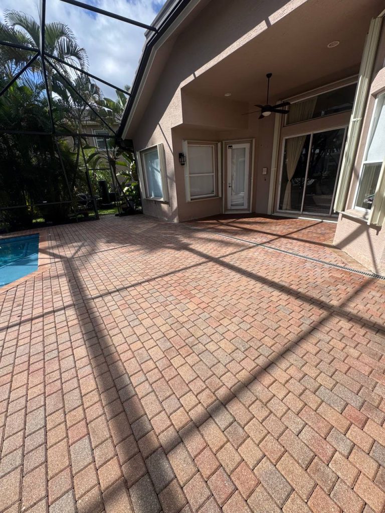 Earlier ground surface around a swimming pool inside a screen enclosure.
