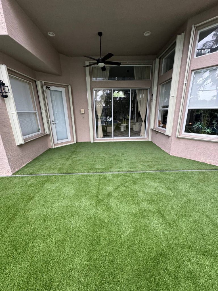 Turf around a swimming pool inside a screen enclosure.