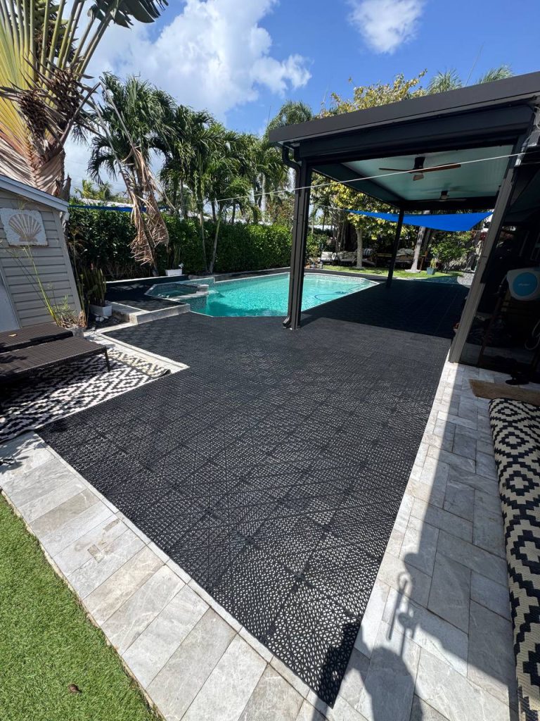 Dark installation underlay around a swimming pool beneath a blue shade sail.