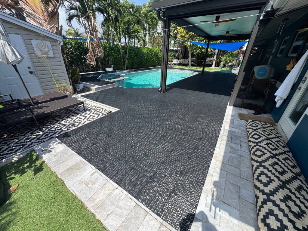 Dark installation underlay around a swimming pool beneath a blue shade sail.